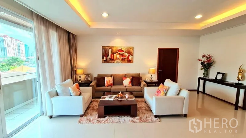 Apartment for rent in Khlong Toei, Bangkok - Living room with sofa set opening to a balcony and city views near BTS Phrom Phong.