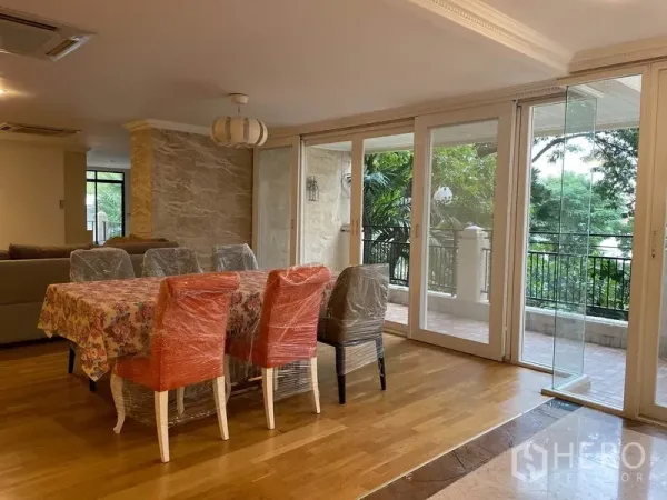 Condominium for rent in Watthana, Bangkok - Dining area with wood flooring opening to the balcony through full-height sliding glass doors.