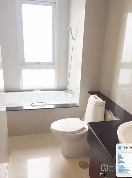 Condominium for rent in Khlong Toei, Bangkok - Bright bathroom with bathtub, window, and modern fixtures.