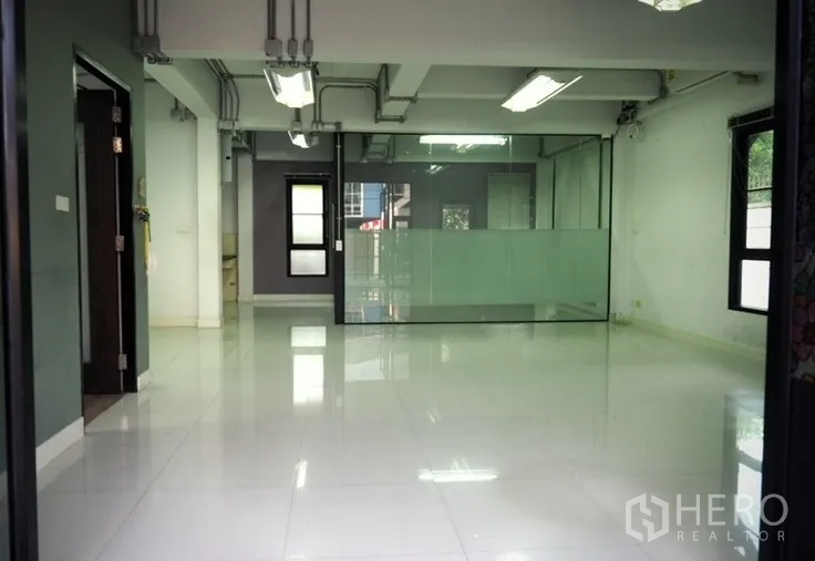 Home Office for rent in Lat Phrao, Bangkok - Open-plan office floor with glossy tiles and a glass-partition meeting room.
