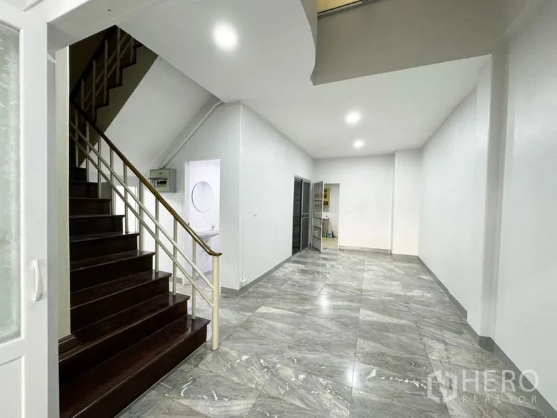 Townhouse for rent or sale in Suan Luang, Bangkok - Ground floor hall with marble-look floor tiles and staircase to upper levels