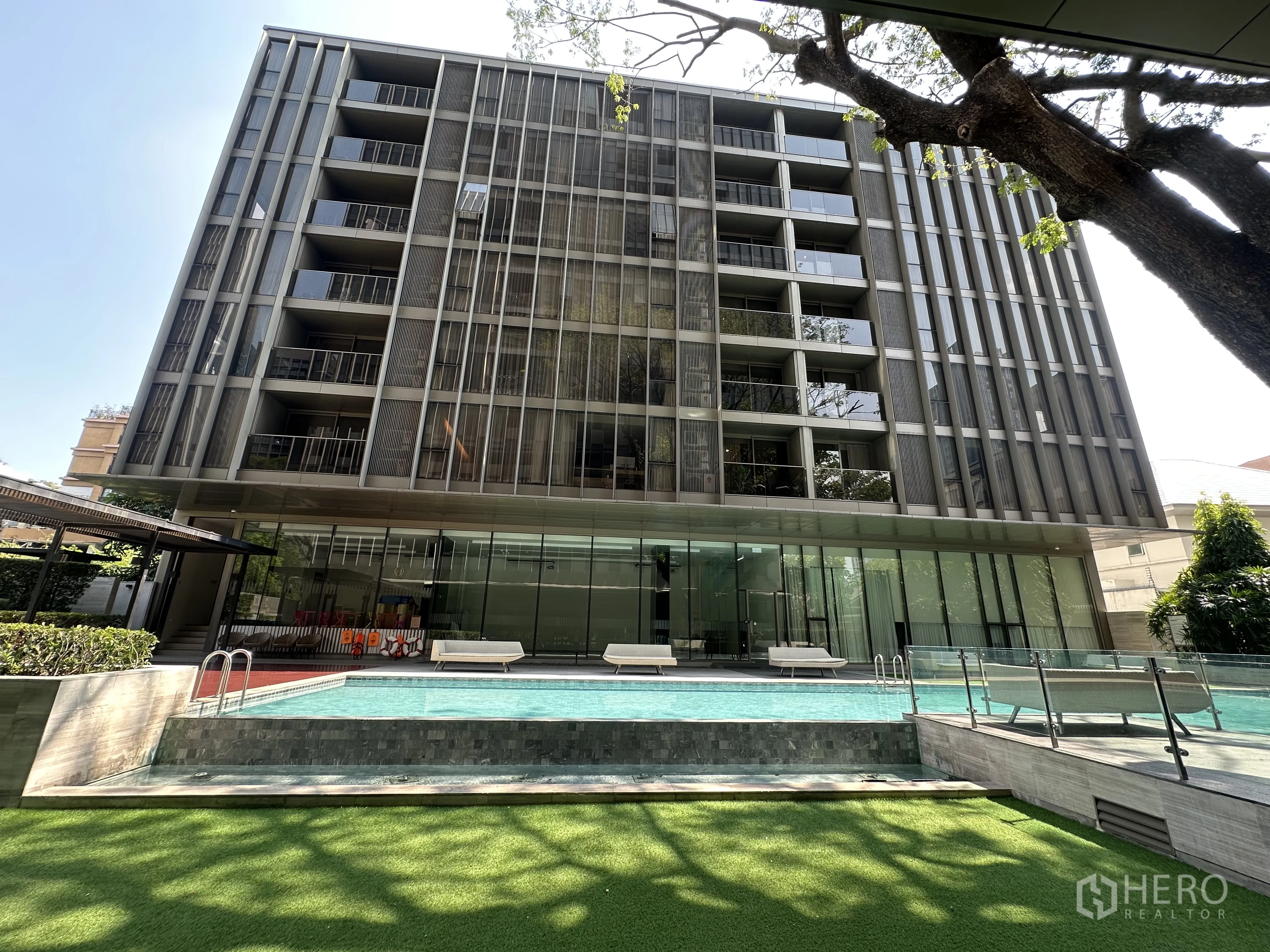 Condominium for rent in Khlong Toei, Bangkok - Modern mid-rise condominium exterior with glass facade and pool deck.