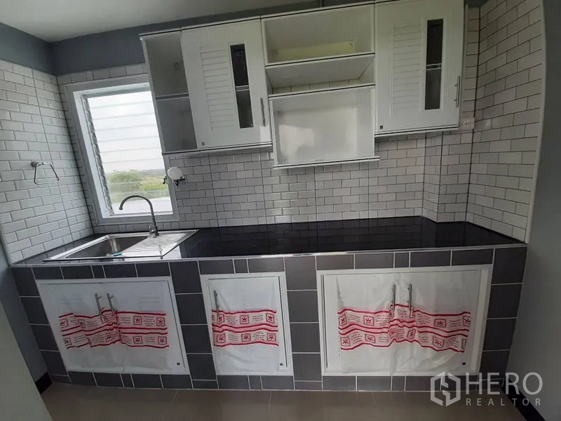 Factory for rent or sale in Lam Luk Ka, Pathum Thani - Built-in pantry with subway tile backsplash, black countertop and window.