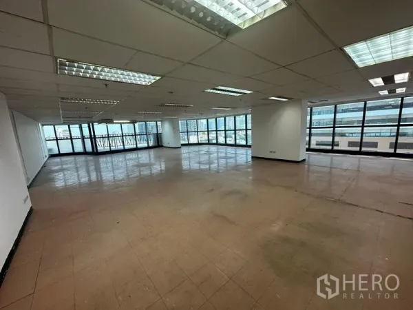 Office Space for rent - Spacious open-plan corner office with grid ceiling lights and wraparound floor-to-ceiling windows overlooking the Ekkamai skyline.