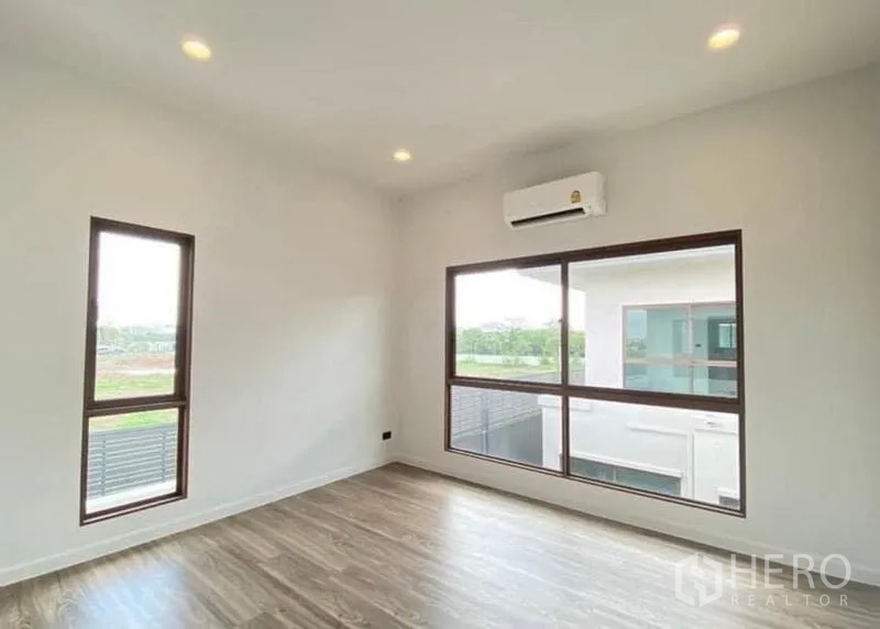 Detached House for sale in Bang Kapi, Bangkok - Corner bedroom with large windows, recessed lights and split-type air conditioner.