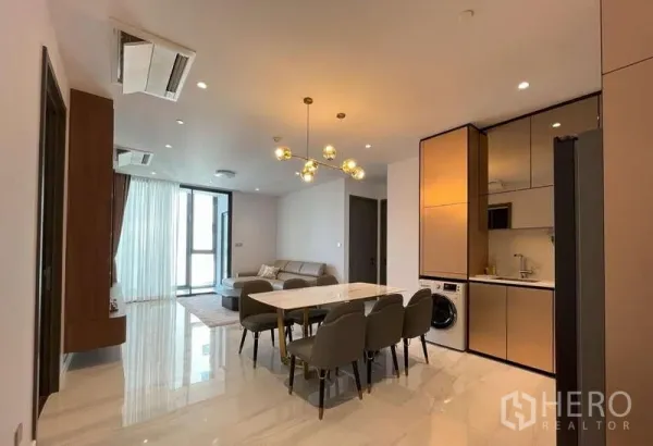 Condominium for rent or sale in Sathon, Bangkok - Open-plan living, dining and sleek kitchenette with gold cabinets and marble flooring.