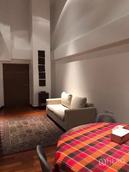 Condominium for rent in Watthana, Bangkok - Cozy living corner with cream sofa, patterned rug and high ceiling in a Thonglor condo.
