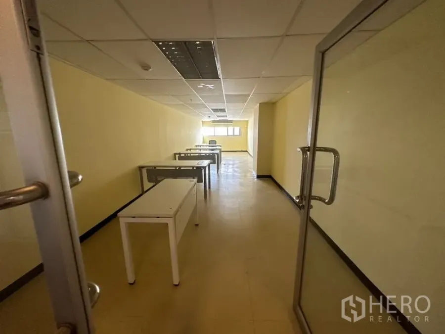 Office Space for rent in Watthana, Bangkok - Long office room with durable flooring, ceiling light panels, work tables and a rear window near Asok.