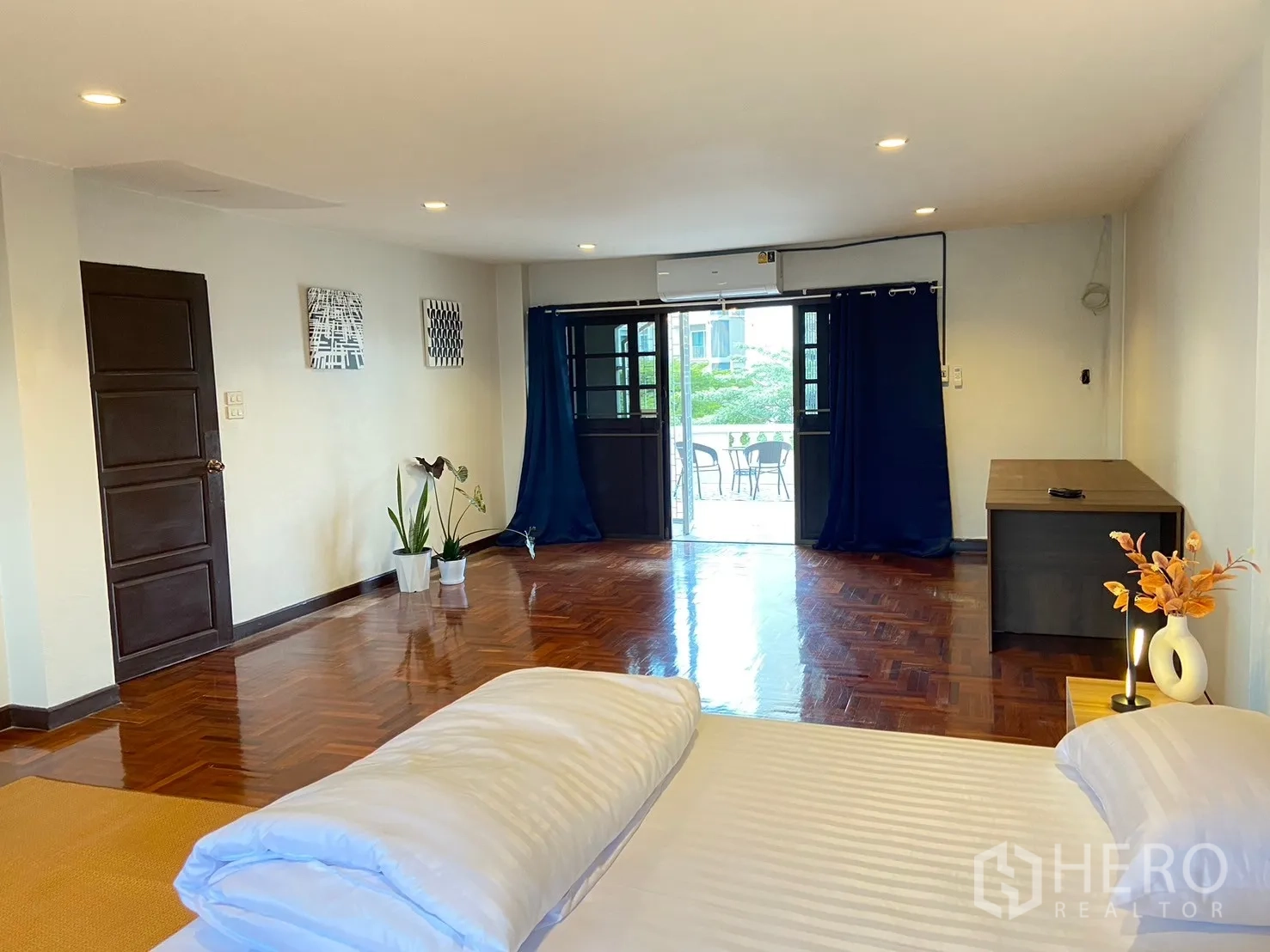 家庭办公室 for rent in Watthana, Bangkok - 卧室带拼花木地板、床、蓝色窗帘的阳台门与空调