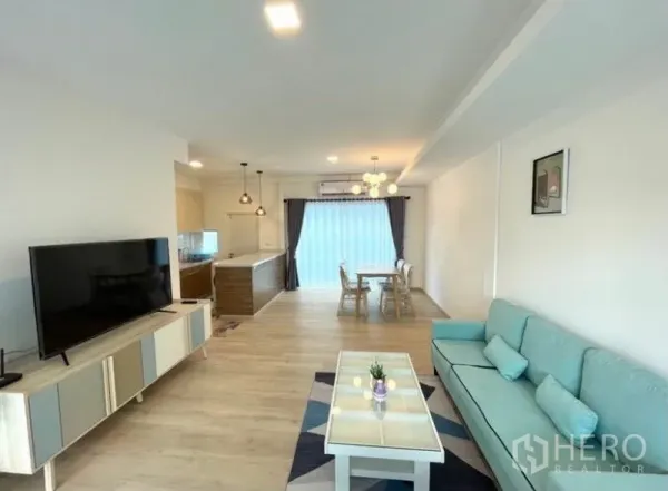 联排别墅 for rent in Prawet, Bangkok - 开放式起居区，沙发、电视柜、餐桌与后方厨房一览。