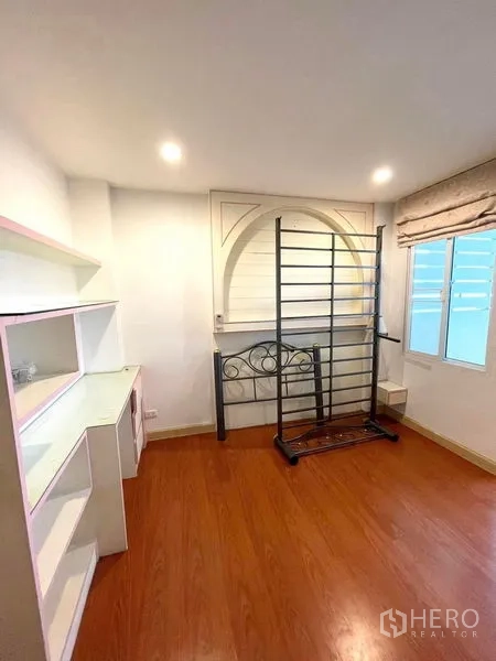 Townhouse for rent in Saphan Sung, Bangkok - Spare room with wood floors, shelving and a metal bed frame beside a window.