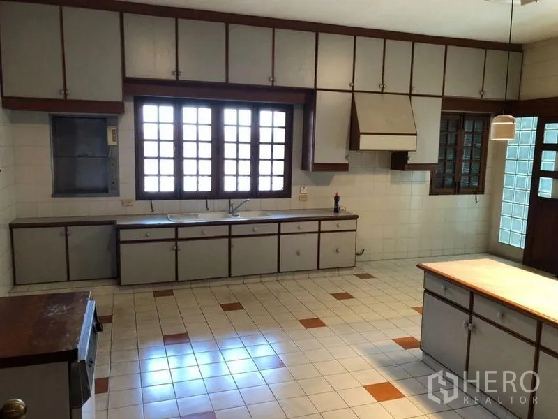 Detached House for sale in Bang Na, Bangkok - Large tiled kitchen with extensive cabinetry, windows and a central island.