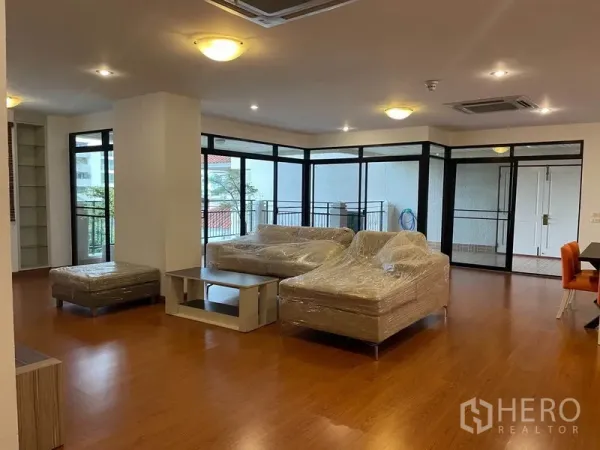 公寓 出租在Watthana, Bangkok - 转角客厅，环绕落地窗，连通封闭阳台区。
