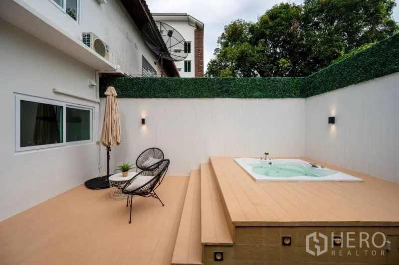 Townhouse for sale in Khlong Toei, Bangkok - Outdoor terrace with in‑ground jacuzzi, steps, rattan chairs and privacy hedge.