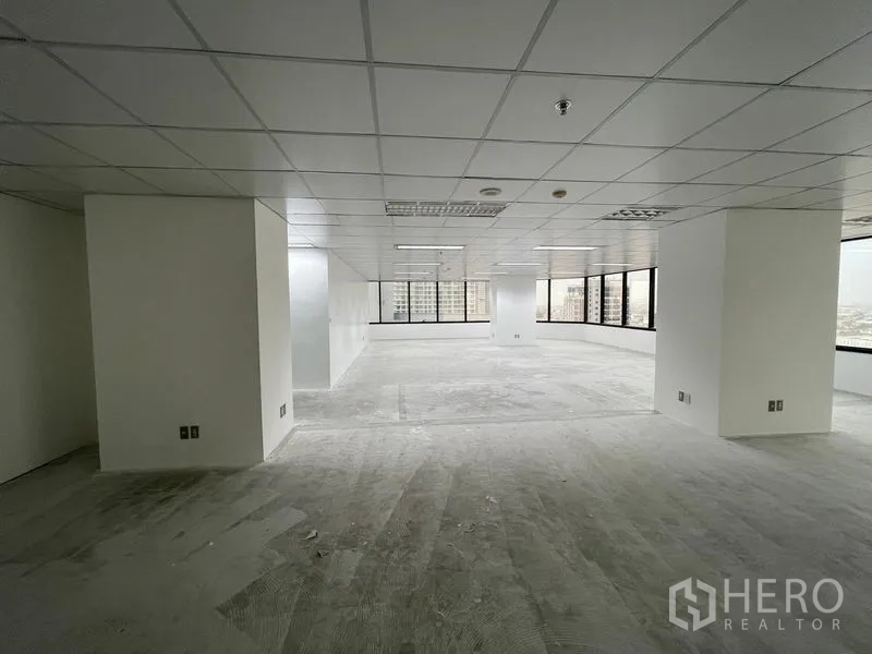 Office Space for rent in Din Daeng, Bangkok - Large empty office with drop ceiling lights and wraparound windows providing natural light.