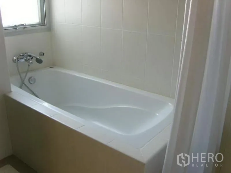 Condominium for rent in Watthana, Bangkok - Bathroom featuring a white bathtub, tiled walls and a small window.