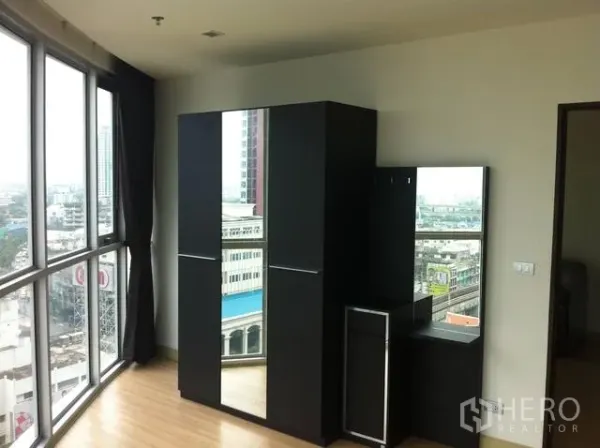 公寓 出租在Watthana, Bangkok - 卧室设转角落地窗，镜面衣柜与梳妆台，可欣赏城市景观。