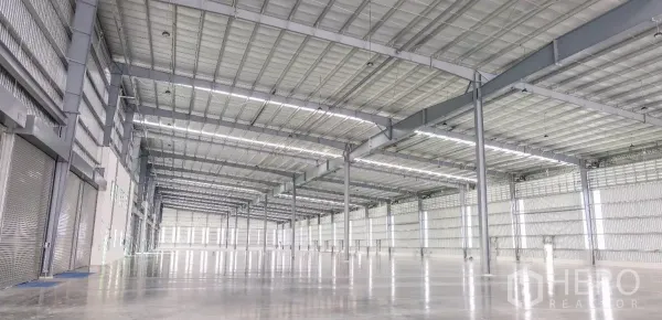 Factory for rent in Bang Sao Thong, Samut Prakan - Spacious high-clear production hall with steel beams, LED strip lighting, and polished concrete flooring.