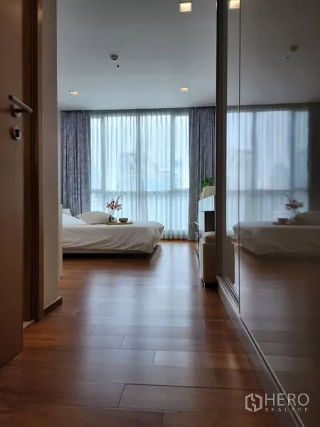 Condominium for rent in Watthana, Bangkok - Hallway with mirrored wardrobe leading into a bright bedroom.