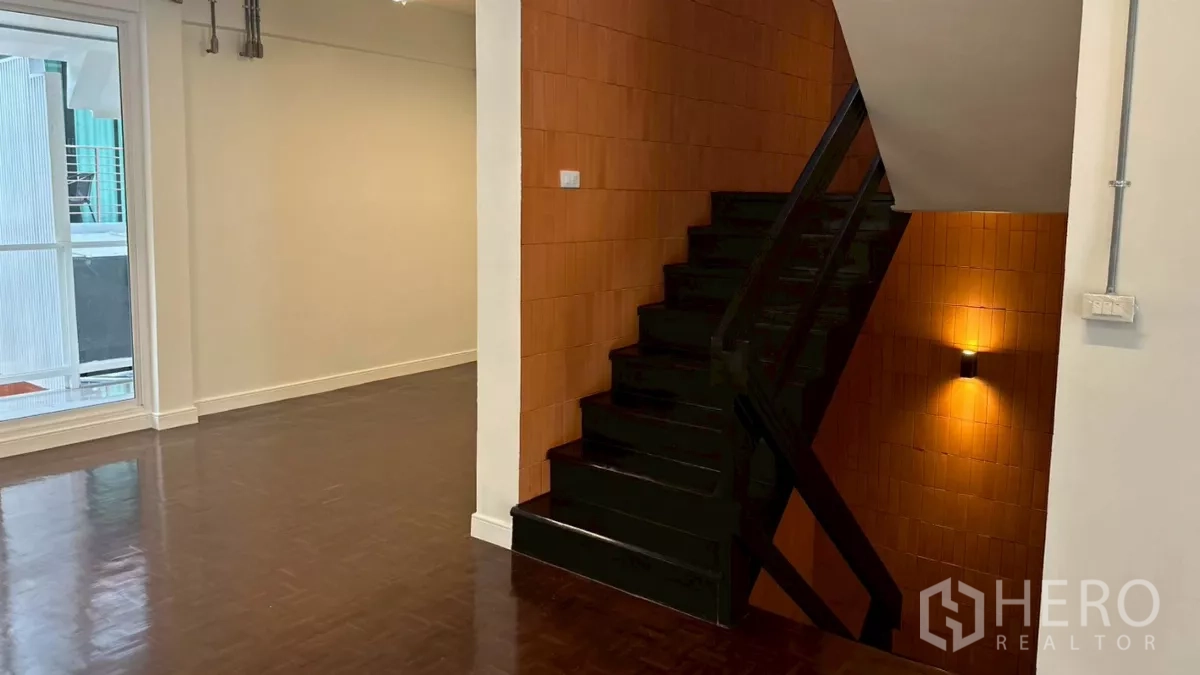 Home Office for rent in Watthana, Bangkok - Stair landing corridor beside textured terracotta wall and black stair rail.