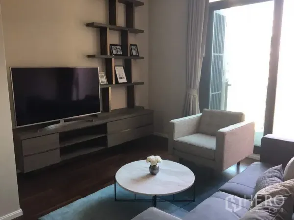 公寓 出租在Watthana, Bangkok - 现代客厅，电视柜与壁架，沙发和圆形茶几，旁有落地窗。