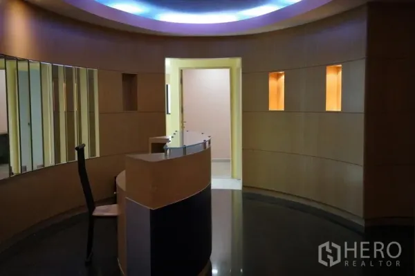 办公空间 出租在Bang Na, Bangkok - 圆形大堂，弧形前台、木质墙面与氛围灯光。