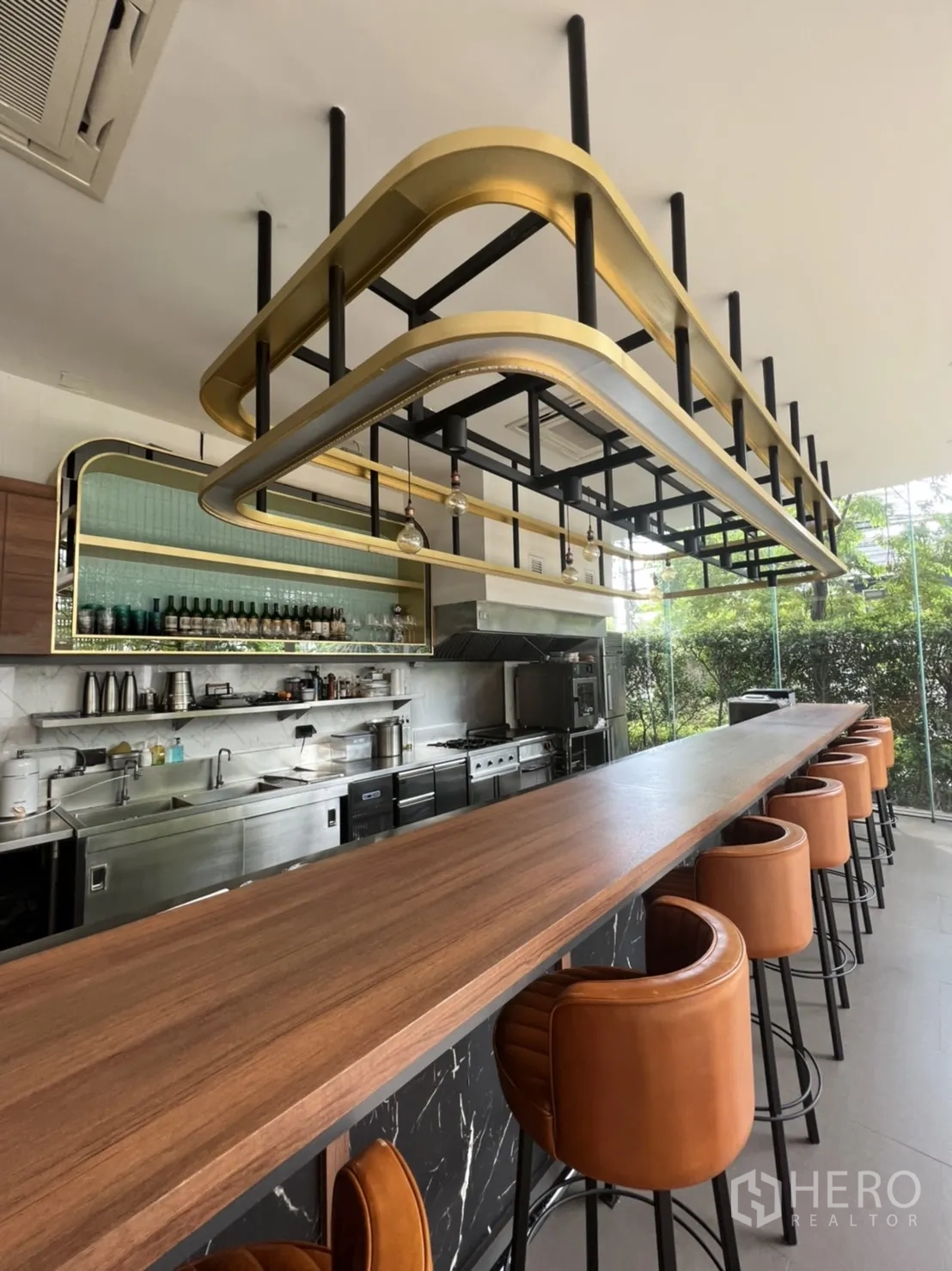 零售空间 出租在Watthana, Bangkok - 吧台近景与金黑色吊架，配高脚座椅与大理石基座。