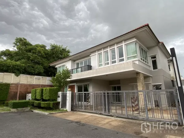 Detached House for rent or sale in Lak Si, Bangkok - Two-storey modern detached house with gated driveway and manicured hedges under a cloudy sky.