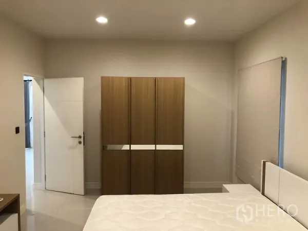 Detached House for rent in Bang Kapi, Bangkok - Bedroom with bed and modern wardrobe, neutral tones and recessed lighting.