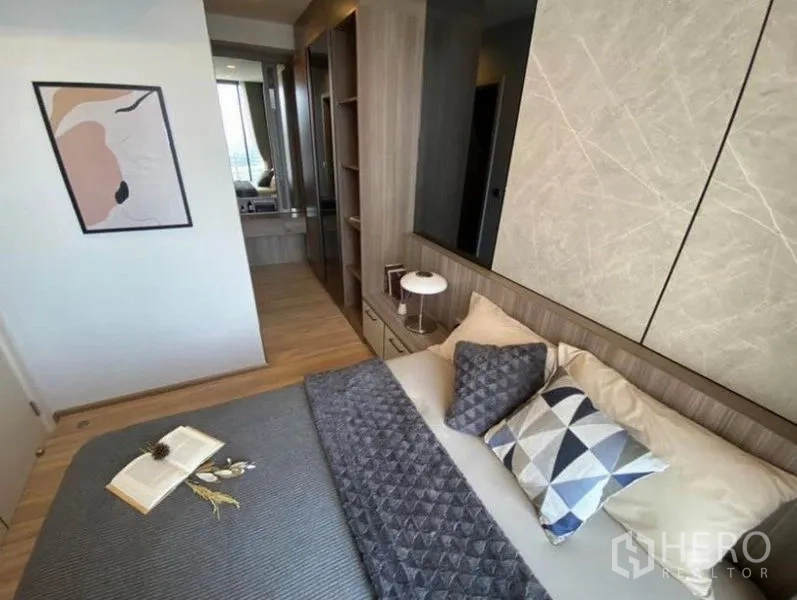 Condominium for rent or sale in Phaya Thai, Bangkok - Bedroom with built-in headboard, wardrobe and warm wood flooring.