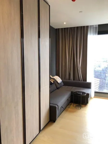 Condominium for rent in Din Daeng, Bangkok - Gray L-shaped sofa by full-height windows and sleek built-in storage.