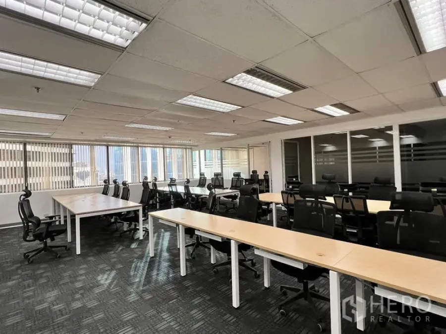 办公空间 出租在Khlong Toei, Bangkok - 宽敞办公区，成排工位与黑色座椅，侧面大窗及玻璃隔间会议室。