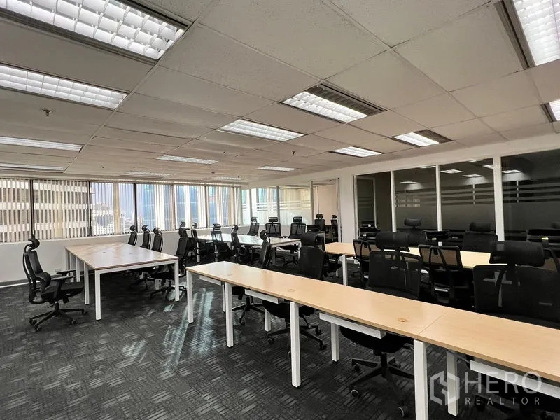 办公空间 出租在Khlong Toei, Bangkok - 宽敞办公区，成排工位与黑色座椅，侧面大窗及玻璃隔间会议室。