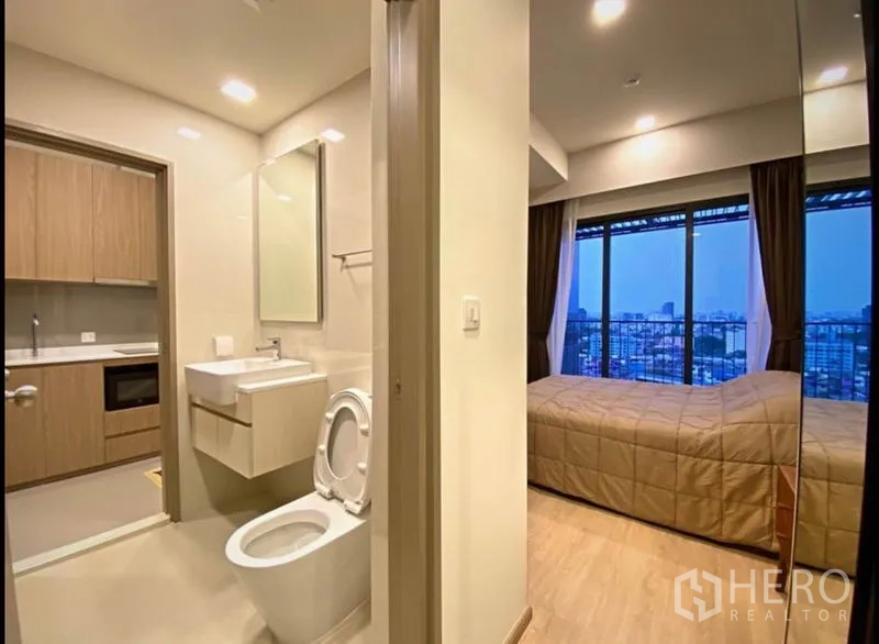 คอนโด ขายในHuai Khwang, Bangkok - มุมมองจากโถงไปยังห้องน้ำสมัยใหม่และห้องนอนที่มีหน้าต่างสูงจรดเพดานเห็นวิวเมือง