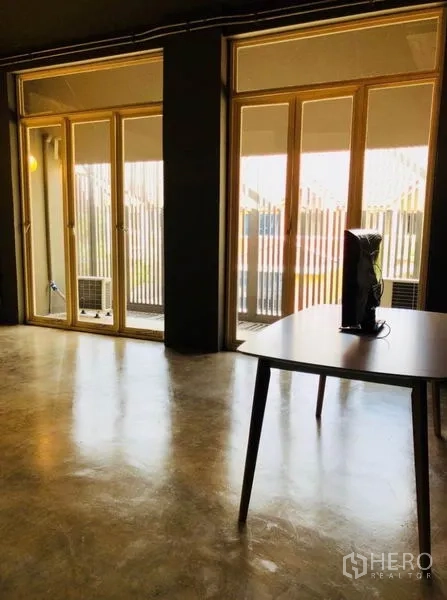Home Office for rent in Huai Khwang, Bangkok - Bright multipurpose room with large sliding doors and concrete floor.