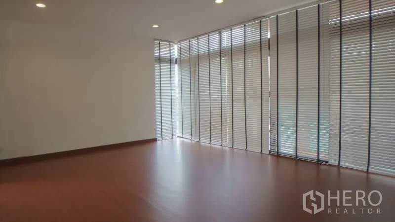 Detached House for rent in Watthana, Bangkok - Spacious living area with floor-to-ceiling blinds, recessed lights, and wood floors.