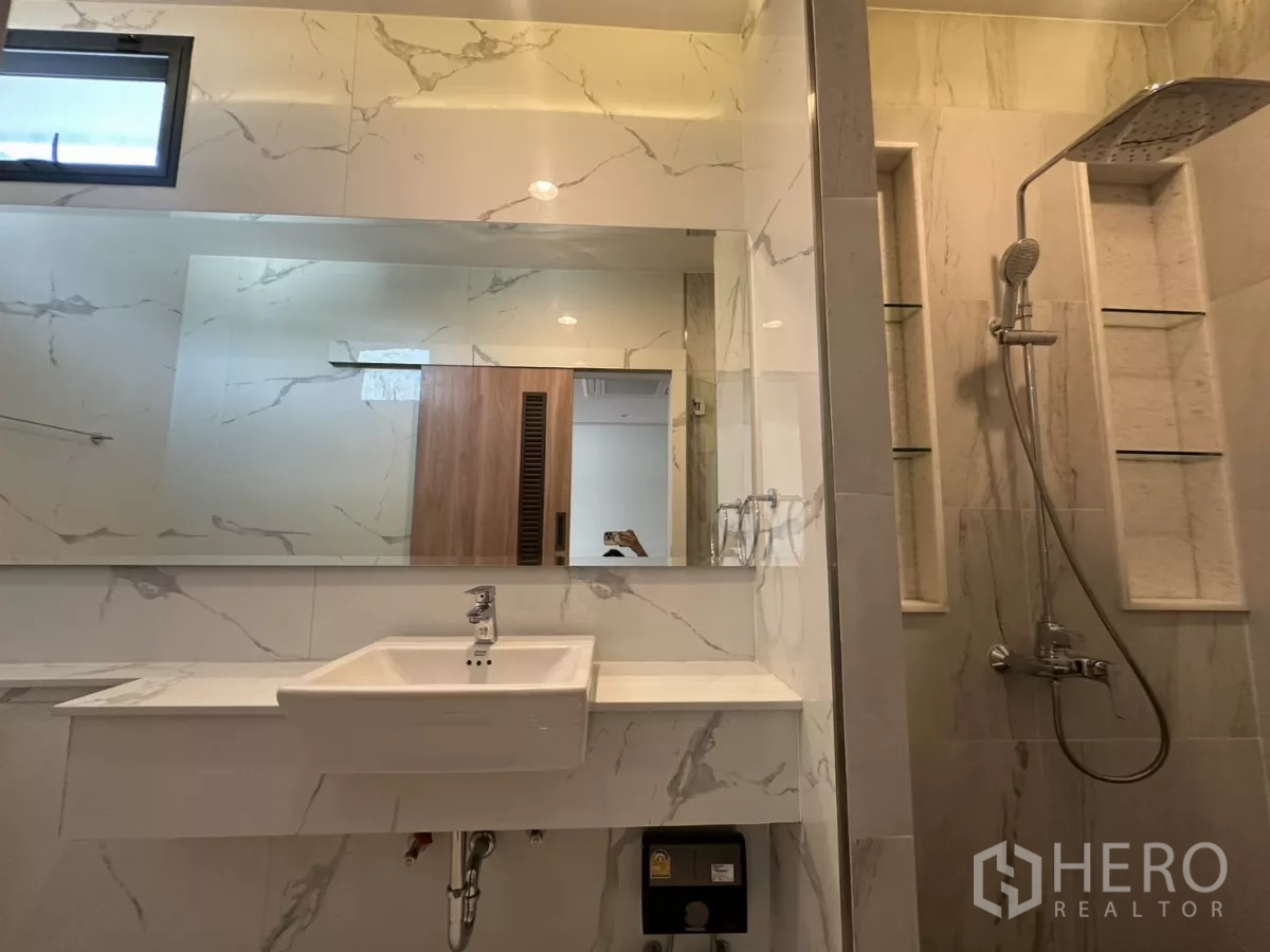 Townhouse for rent in Watthana, Bangkok - Bathroom with marble-look tiles, wide mirror, and rain shower.