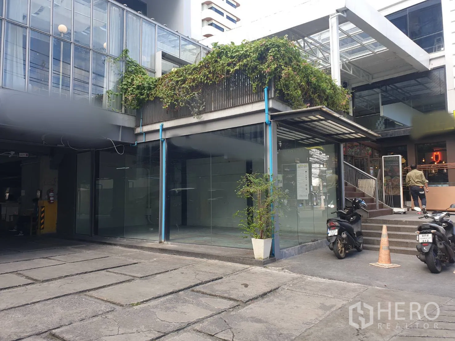 Retail Space for rent in Khlong Toei, Bangkok - Corner shop space with floor-to-ceiling windows beside exterior stairs in a modern complex.