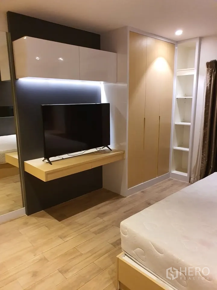 Condominium for rent in Watthana, Bangkok - Alternate bedroom angle showing TV on floating shelf with built-in wardrobe and shelves.