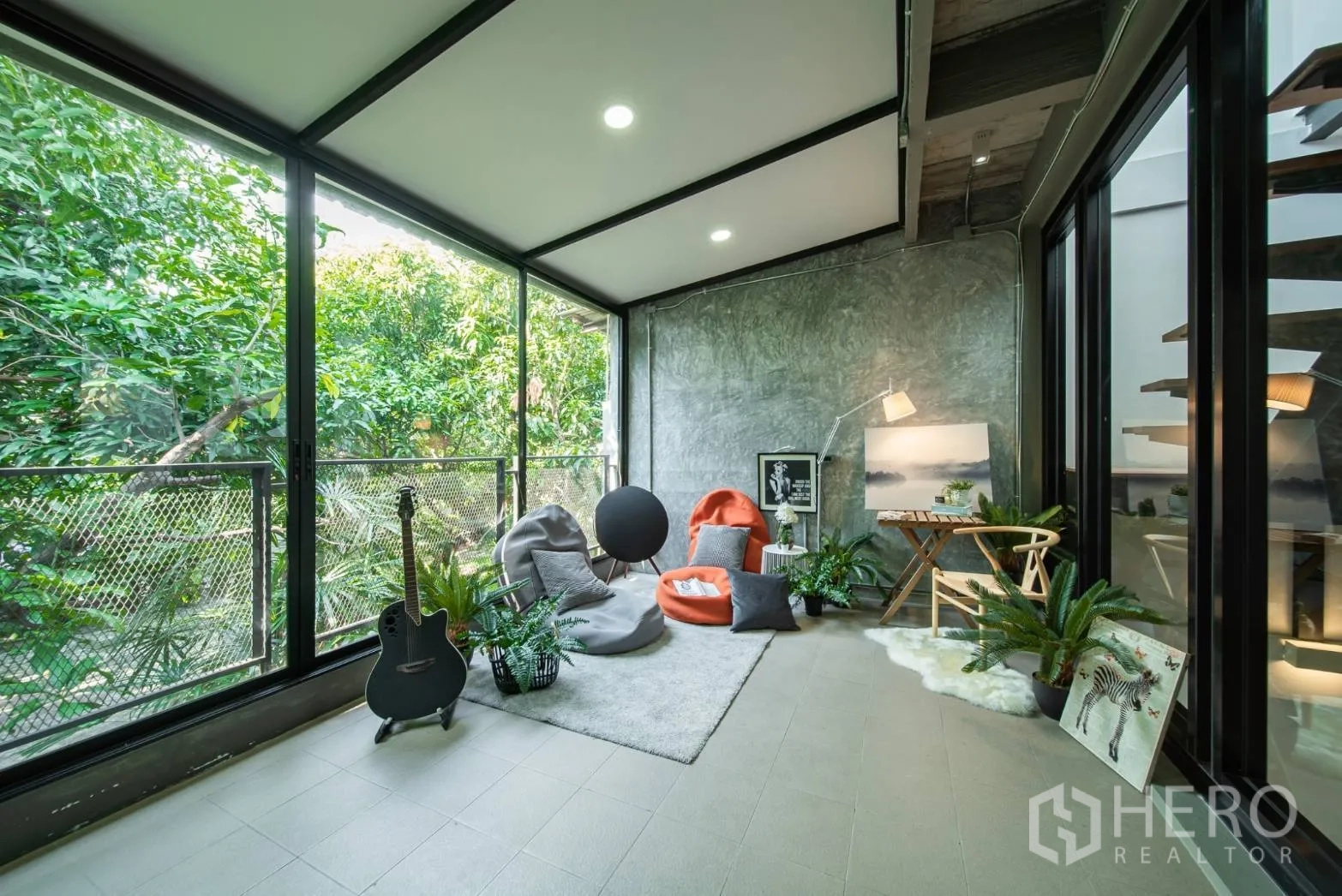 Townhouse for rent in Watthana, Bangkok - Sunlit green-view lounge with floor-to-ceiling windows, beanbags and indoor plants.
