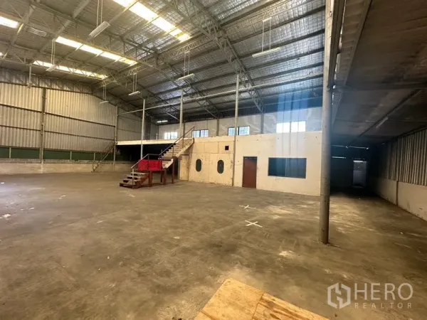 Warehouse for rent in Suan Luang, Bangkok - Open industrial floor with concrete slab, internal office block and mezzanine staircase.