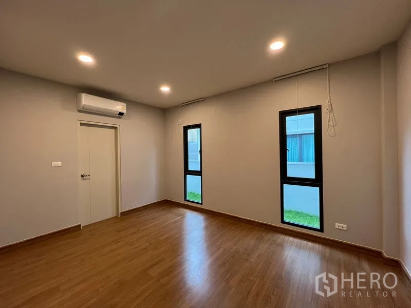 Detached House for rent or sale in Bang Phli, Samut Prakan - Ground-floor bedroom with two tall narrow windows and air conditioner.
