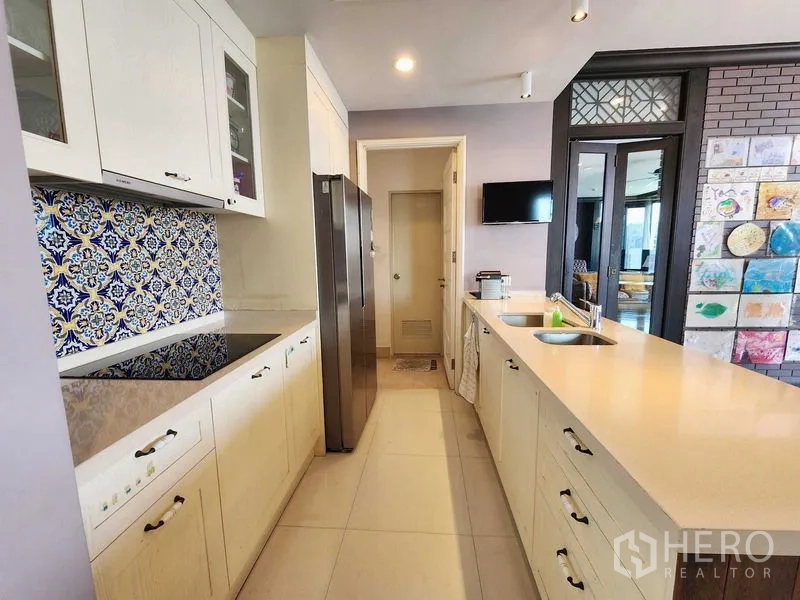 Condominium for sale in Khlong Toei, Bangkok - Galley kitchen with patterned tile backsplash, long countertops and double sink.