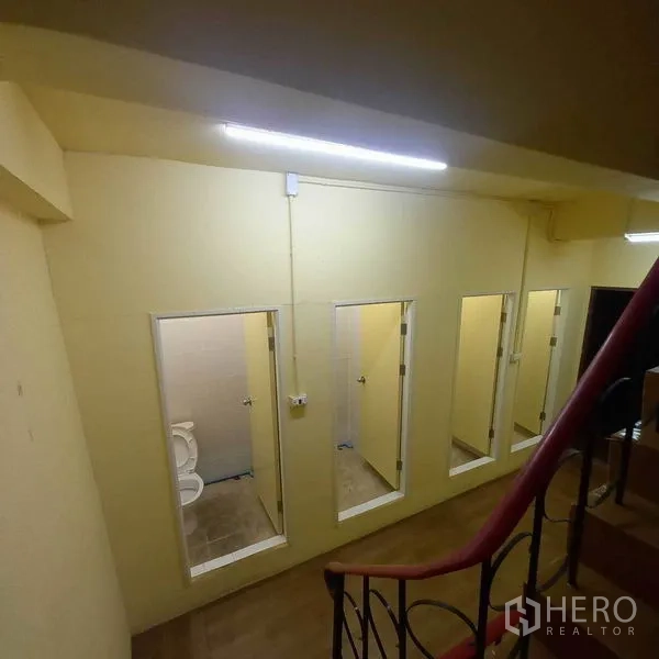 Shophouse for rent in Watthana, Bangkok - Row of tiled bathrooms with toilets viewed from the stairwell