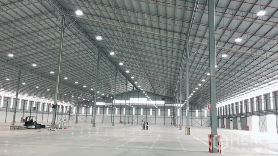 Warehouse for rent in Si Racha, Chon Buri - Expansive high-clearance warehouse interior with steel truss roof, bright LED lighting and polished concrete floor.