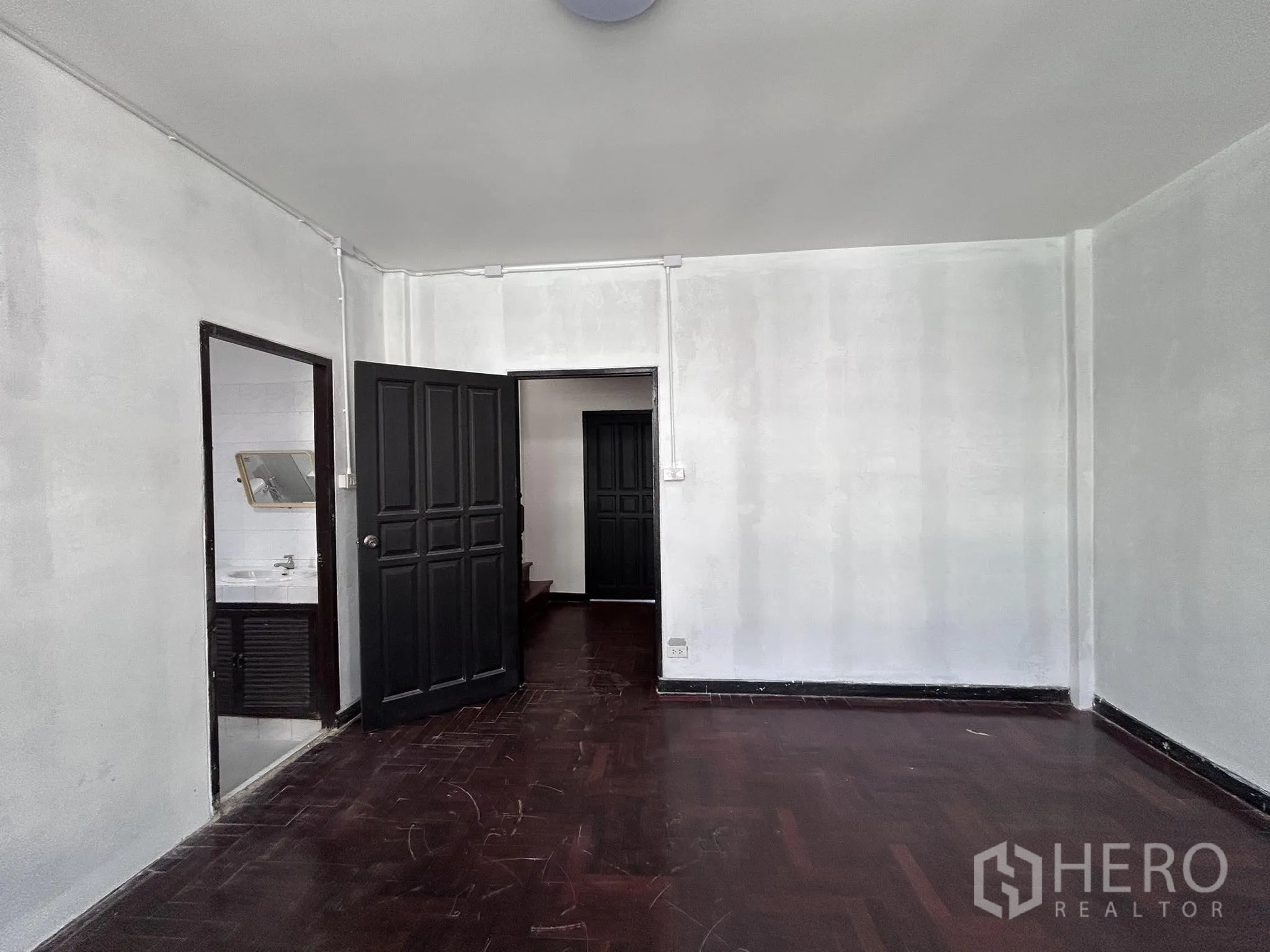 家庭办公室 for rent or sale in Watthana, Bangkok - 宽敞房间，深色木地板，带通往浴室的门。