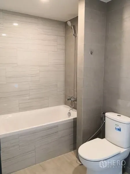 公寓 出租或出售在Watthana, Bangkok - 现代浴室，带浴缸、顶喷淋浴、浅灰色瓷砖与马桶。