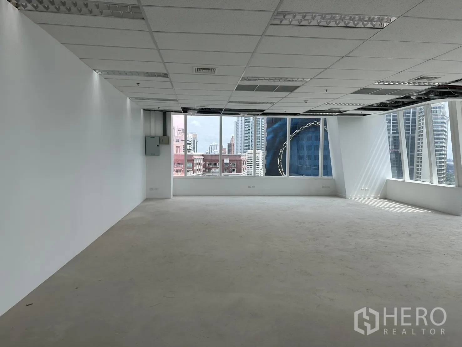 Office Space for rent in Watthana, Bangkok - Open-plan office with white walls, drop ceiling, and large corner windows overlooking the Bangkok skyline.
