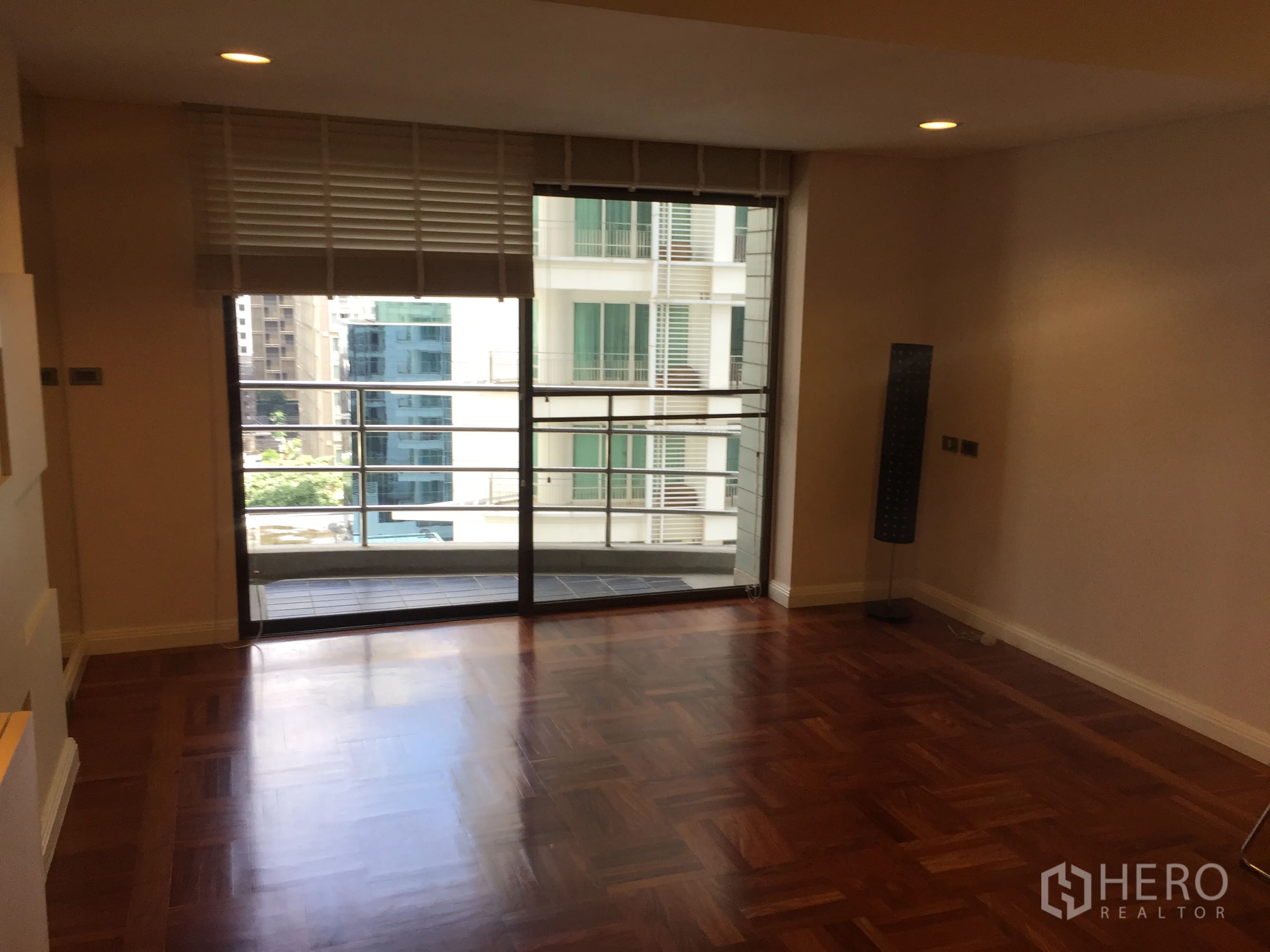 公寓 出租在Pathum Wan, Bangkok - 客厅设推拉玻璃门通向阳台，可见城市景观。