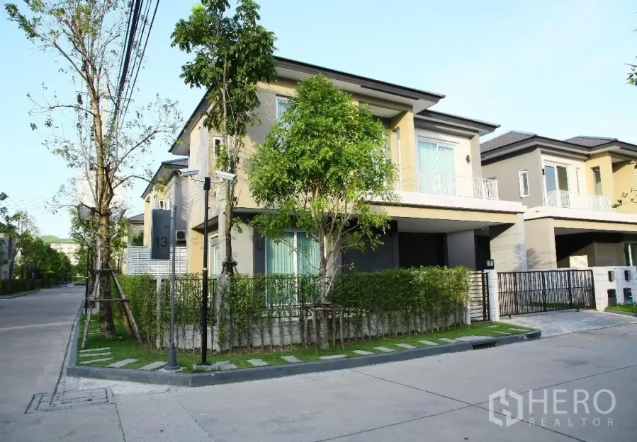 บ้าน ให้เช่าหรือขายในBang Na, Bangkok - มุมมองแปลงมุมของบ้านเดี่ยวสองชั้นสไตล์โมเดิร์น รั้วรอบ พร้อมต้นไม้และถนนเงียบสงบ